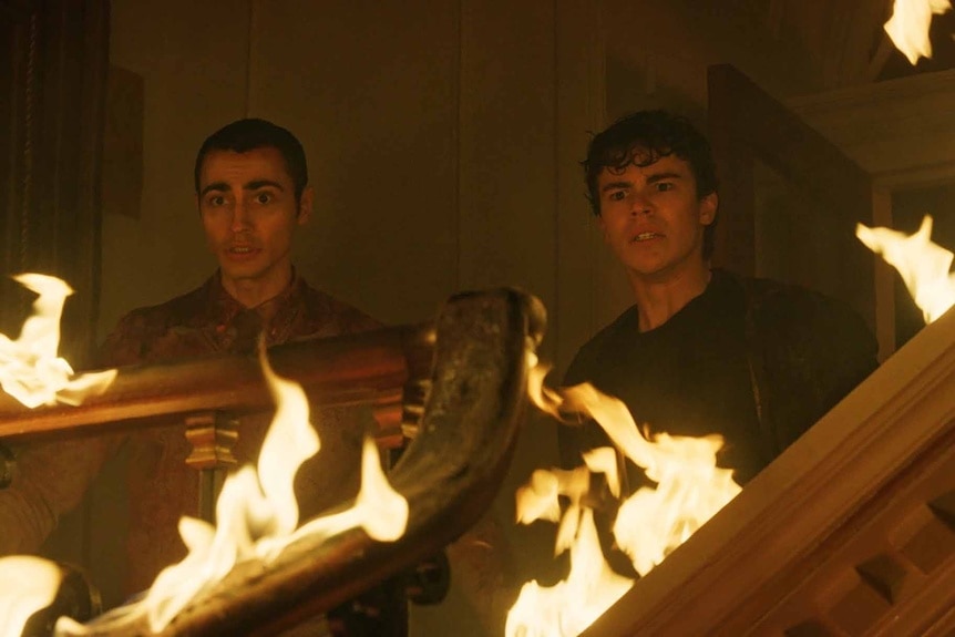Timmy Nash and Jake Wheeler stands near burning furniture on Chucky Episode 308.