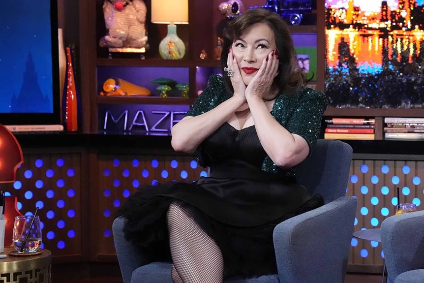 Jennifer Tilly holds her hands to her cheeks on Watch What Happens Live with Andy Cohen.