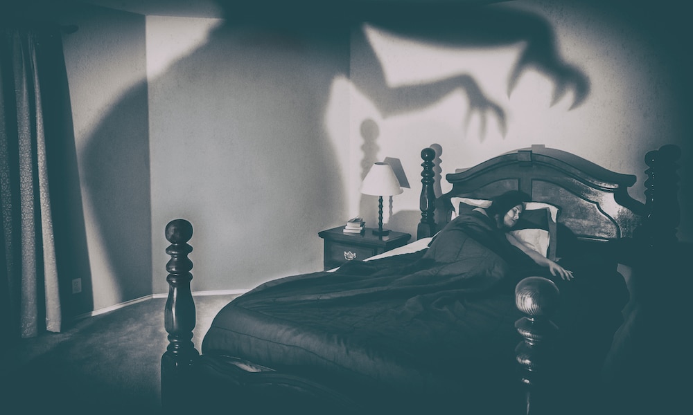 Woman Sleeping On Bed With Spooky Shadow On Wall