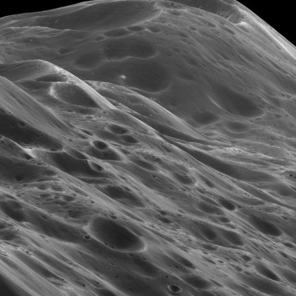 An extreme close-up of the ridge of Saturn’s moon Iapetus, showing heavily cratered individual peaks. Credit: NASA/JPL/Space Science Institute