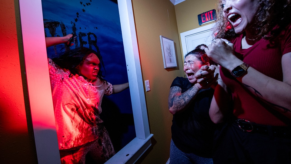An Actor and scared people during Halloween Horror Nights The Exorcist Believer