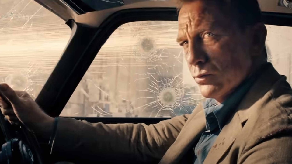 James Bond (Daniel Craig) drives a car with bullet holes in No Time to Die (2021).