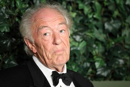 Michael Gambon wears a suit and bow tie.