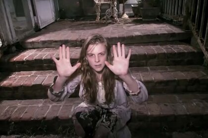 A disheveled Nell Sweetzer (Ashley Bell) holds holds her hands up in The Last Exorcism (2010).