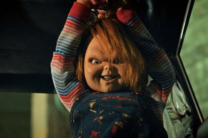 Chucky smiles murderously while holding a weapon above his head in Chucky 303.