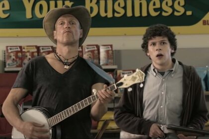 Tallahasee (Woody Harrelson) holds a banjo with Columbus (Jesse Eisenberg) by his side in the grocery store in Zombieland (2009).