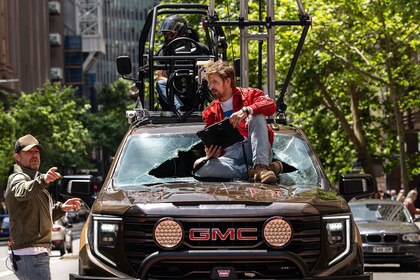 Ryan Gosling sits on the hood of a car as he's directed by Eric Laciste