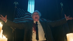 Charles Lee Ray cackles near an American flag and candles in Chucky Episode 307.