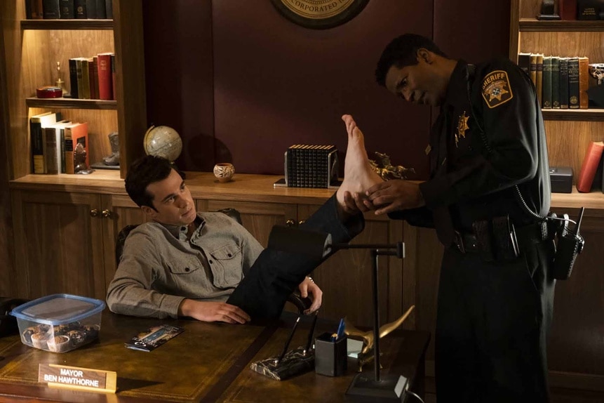 Sheriff Mike Thompson assesses Mayor Ben Hawthorne's foot in Resident Alien Episode 302.