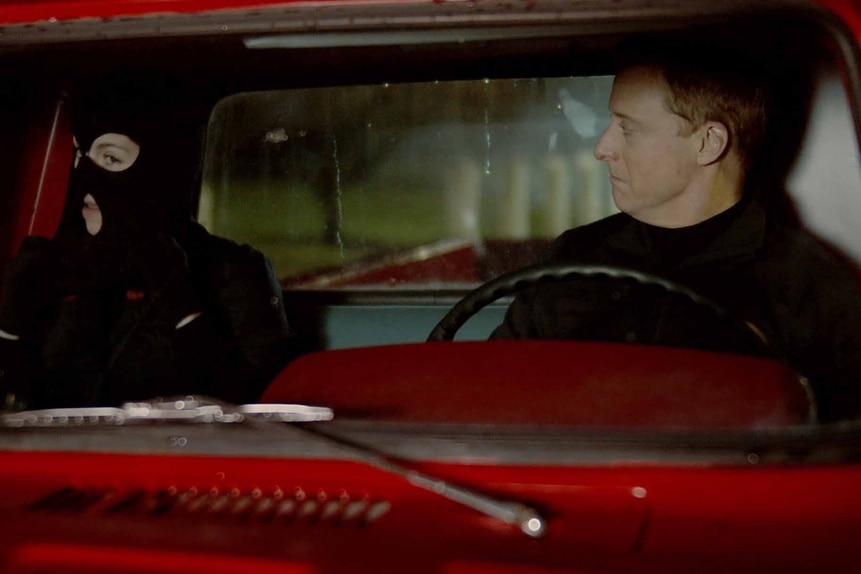 D'Arcy Bloom, in a ski mask, sits in a red truck with Harry Vanderspeigle in Resident Alien Episode 302.