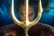Aquaman (Jason Momoa) holds a golden trident in front of his face in Aquaman and the Lost Kingdom (2023).