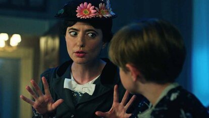 Annie Gilpin (Sarah Sherman) wears a flower hat and uses her hands to speak to a child in Chucky Season 3 Episode 4.