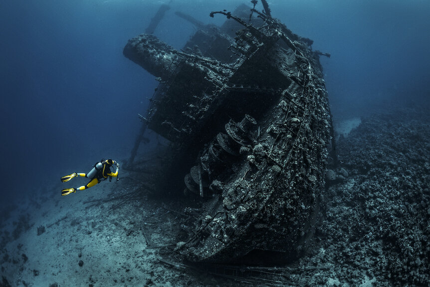 Scuba diver observing a large shipwreck in the Red Sea