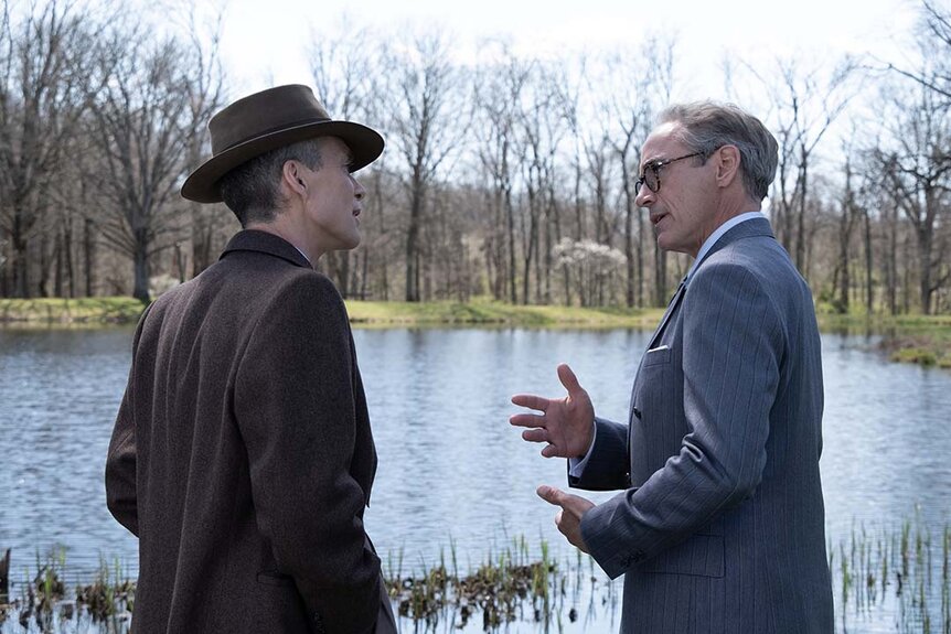 Cillian Murphy and Robert Downey Jr chat near a pond in Oppenheimer (2023).