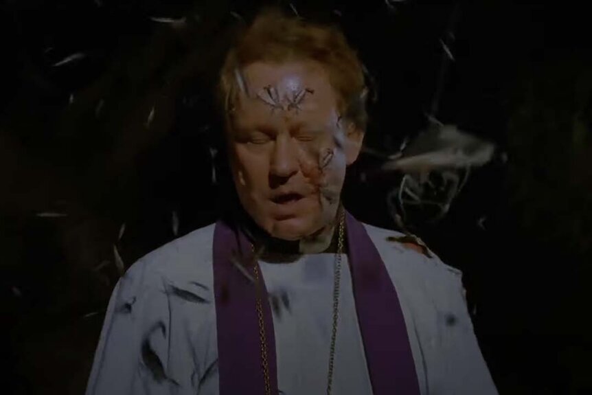 Lankester Merrin (Stellan Skarsgård) covered in bugs in his priest uniform in Dominion: Prequel to the Exorcist (2005).
