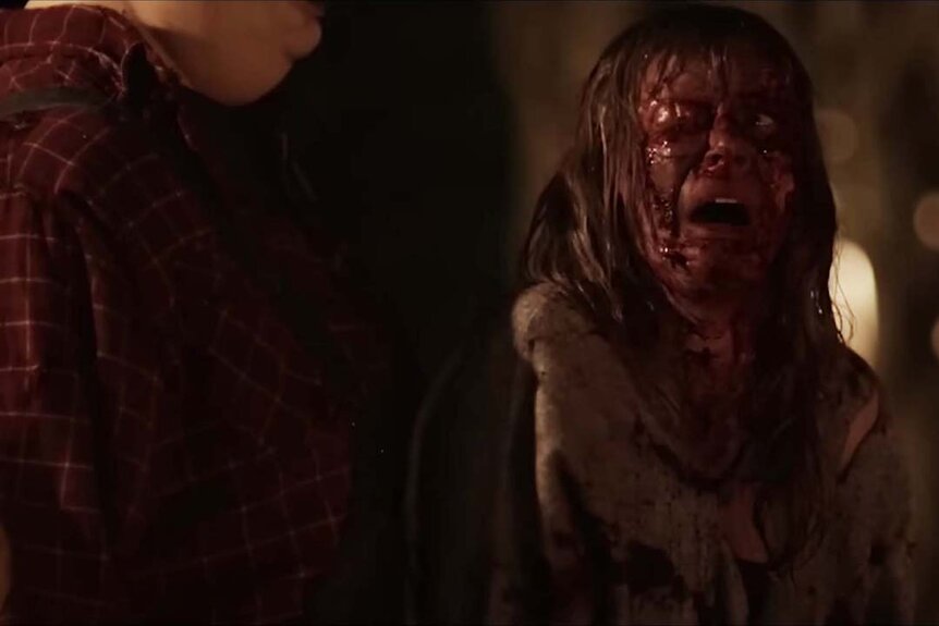 A bloodied girl turns to look at Pooh in fear in Winnie the Pooh: Blood and Honey Trailer (2023)