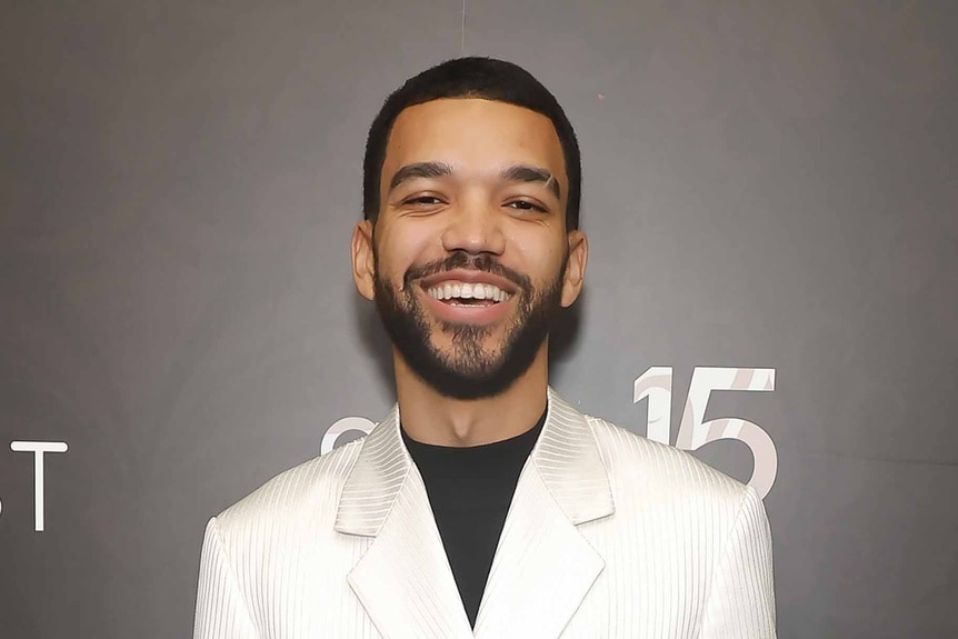 Justice Smith smiles in a white suit.