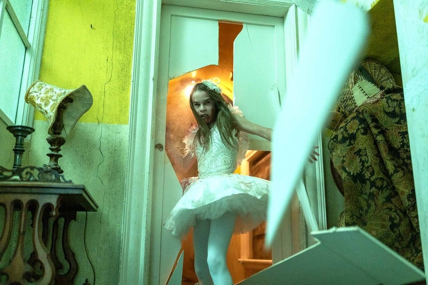 Abigail (Alisha Weir) busts through a door in Abigail (2024).