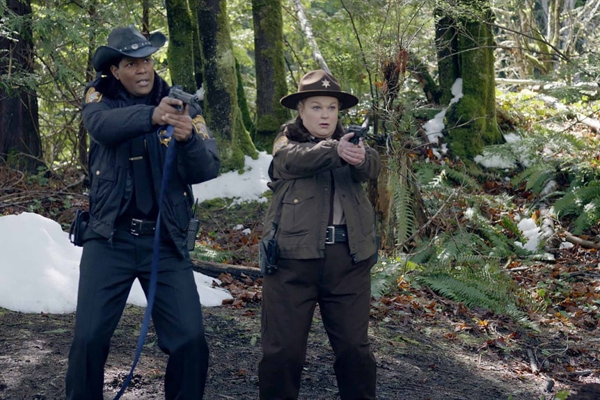 Sheriff Mike Thompson and Deputy Liv Baker point guns in the woods on Resident Alien Episode 308.