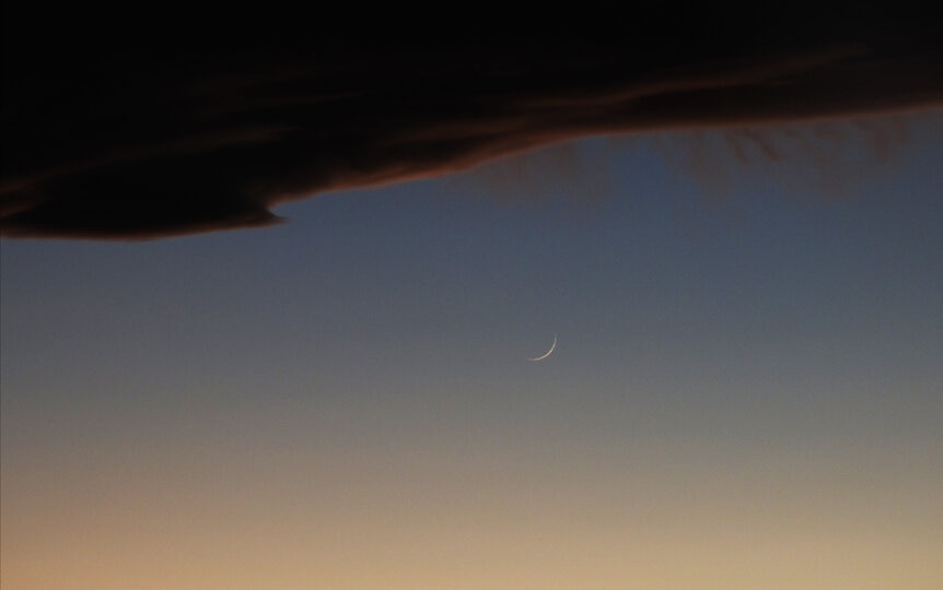 The thin crescent Moon sets just under the cloud bank caused by air rising dramatically over the Rocky Mounatins. Credit: Phil Plait