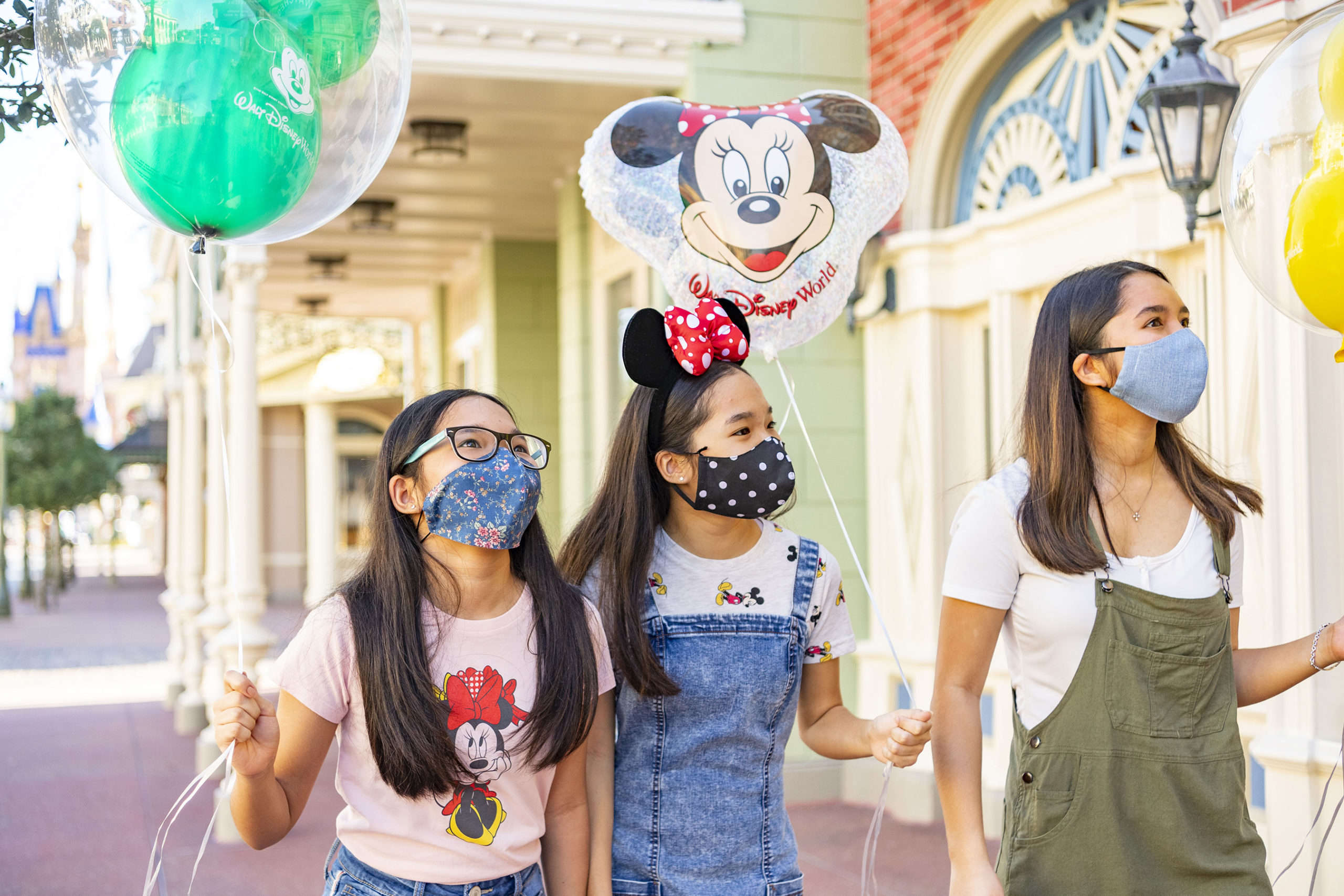 Three guests holding Disney balloons walking down Main Street, USA at Disney's Magic Kingdom