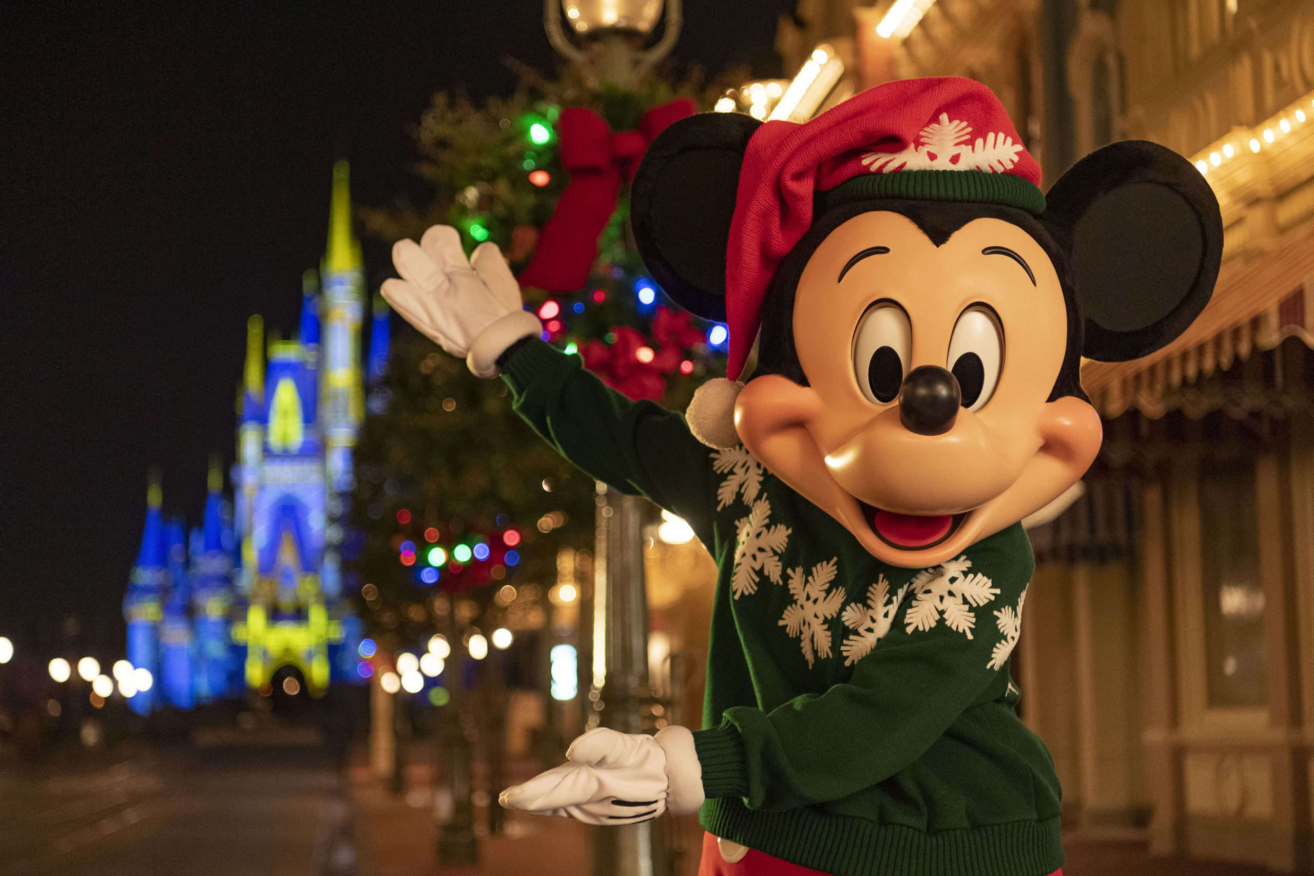 Mickey Mouse dressed for winter and pointing at the castle