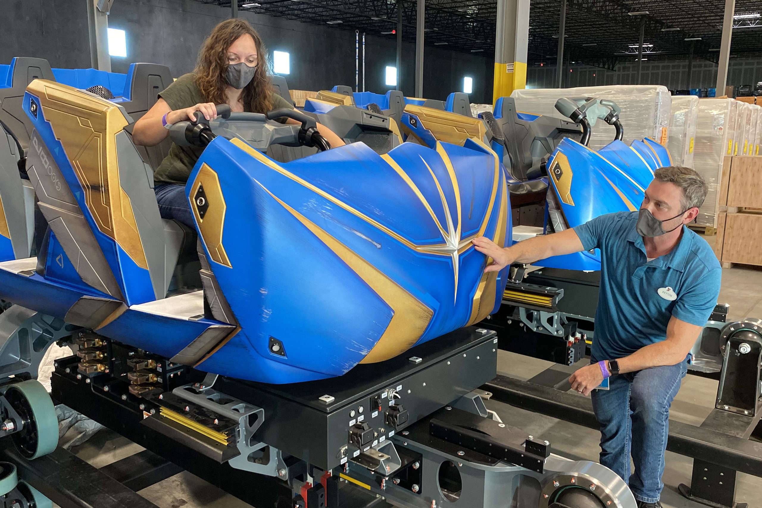 Two people working on the colorful roller coaster ride vehicle that will be used for the Guardians of the Galaxy: Cosmic Rewind ride