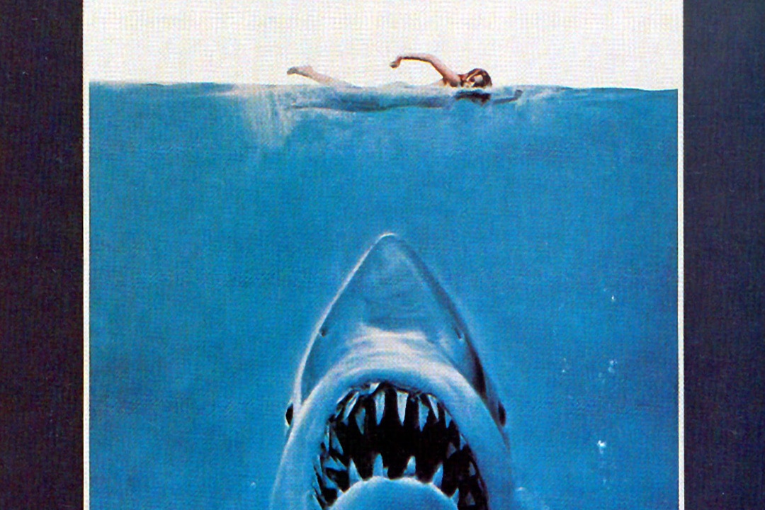 The Jaws (1975) Poster featuring a shark encroaching upon a swimmer.