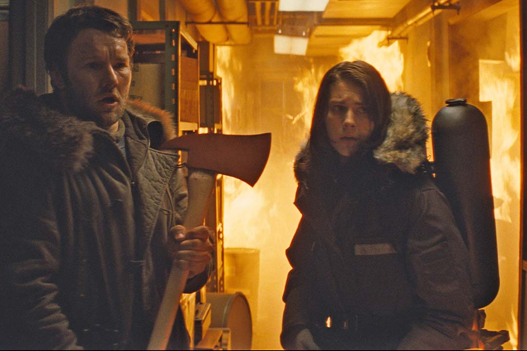 Sam Cartter (Joel Edgerton) holds an ax with Kate Llyod (Mary Elizabeth Winstead) in a fiery hallway in The Thing (2011).