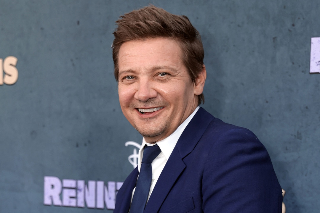 Jeremy Renner smiles in a blue suit.