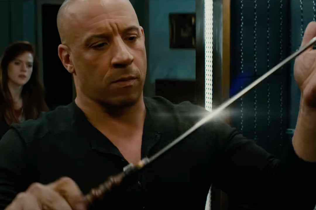 Kaulder (Vin Diesel) inspects a sparkly sword as a woman looks on in the background in The Last Witch Hunter (2015).