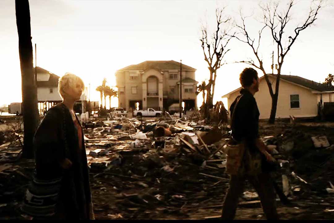Samantha Winden (Whitney Able) and Andrew Kaulder (Scoot McNairy) walk past wreckage in front of houses in Monsters (2010).