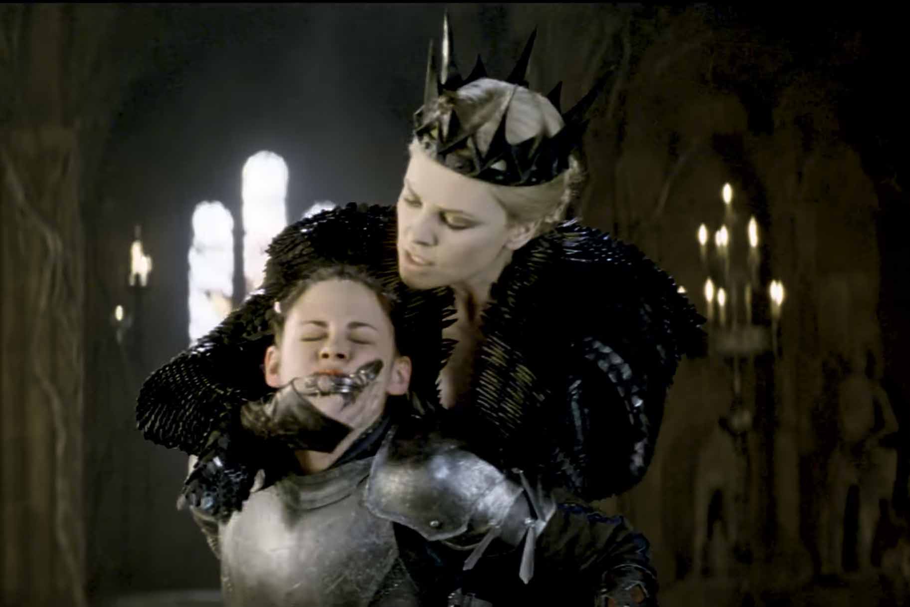 Queen Ravenna (Charlize Theron) violently holds Snow White (Kristen Stewart) in Snow White and the Huntsman (2012).