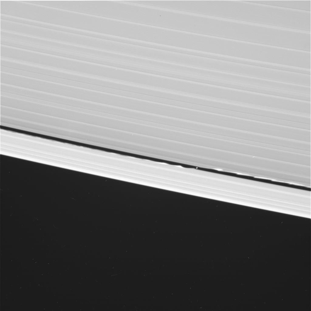 Cassini took this wide-angle shot of Daphnis around the same time as the narrow angle one. Note how far the waves go around the rings. Saturn is to the upper right. This is a raw image, so there are some blemishes that aren't real objects. Credit: NASA/JP