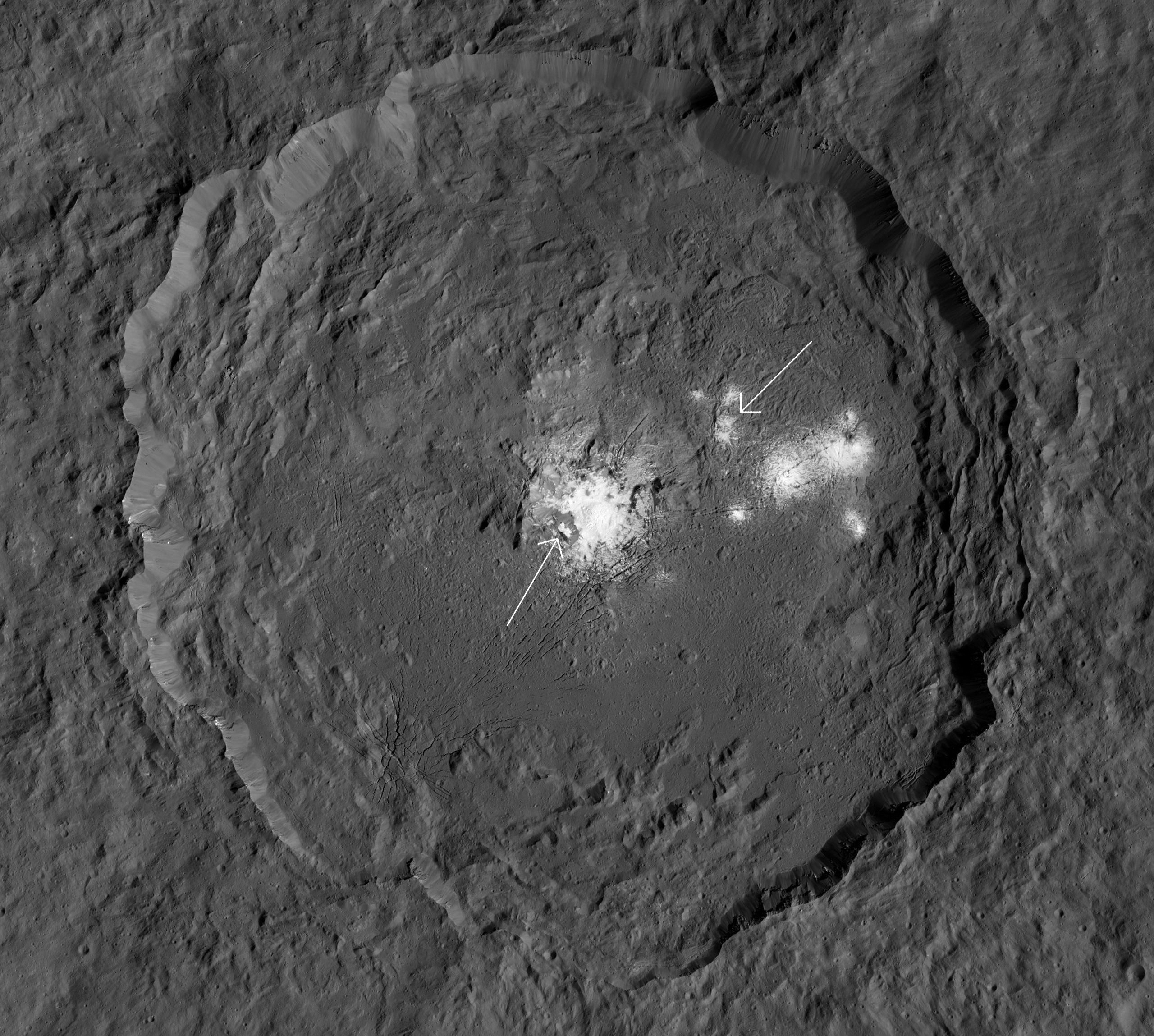 Occator crater, a 92-kilometer-wide impact feature on Ceres, is covered in mineral deposits dredged up from the interior. Cerealia Facula is arrowed (left) as well as Vinalia Faculae (right). Credit: NASA/JPL-Caltech/UCLA/MPS/DLR/IDA/PSI / Phil Plait
