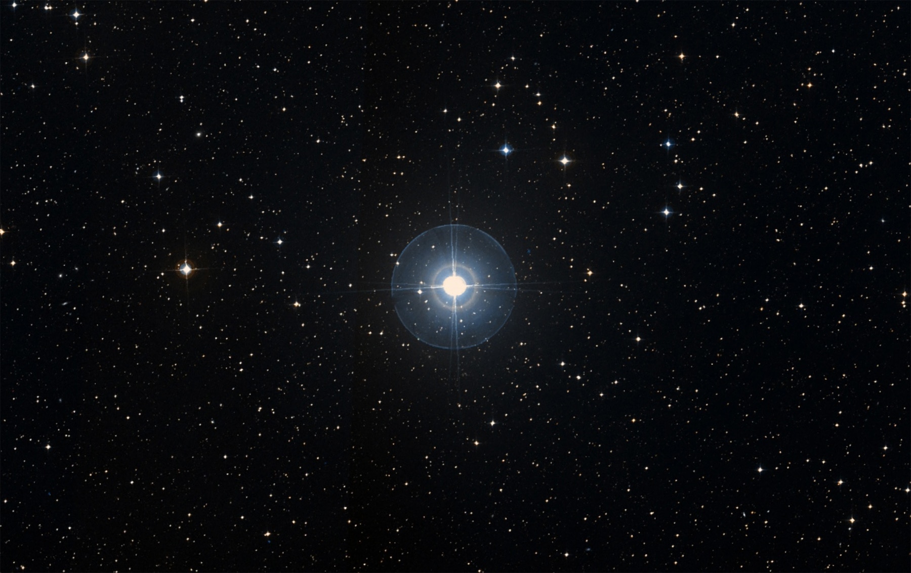 Beta Pictoris (centered; the rings and lines are image artifacts caused by the telescope) is a young nearby star with a disk of dust and at least two planets orbiting it. Credit: SIMBAD / DSS