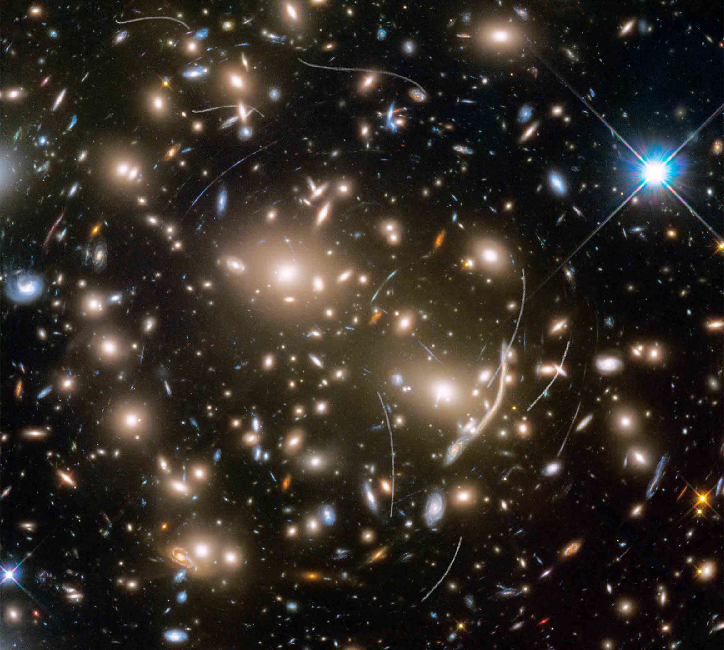Abell 370 provides a dramatic backdrop for quite a few asteroids, seen as curved tracks in this Hubble image. Credit: NASA, ESA, and B. Sunnquist and J. Mack (STScI) Acknowledgment: NASA, ESA, and J. Lotz (STScI) and the HFF Team