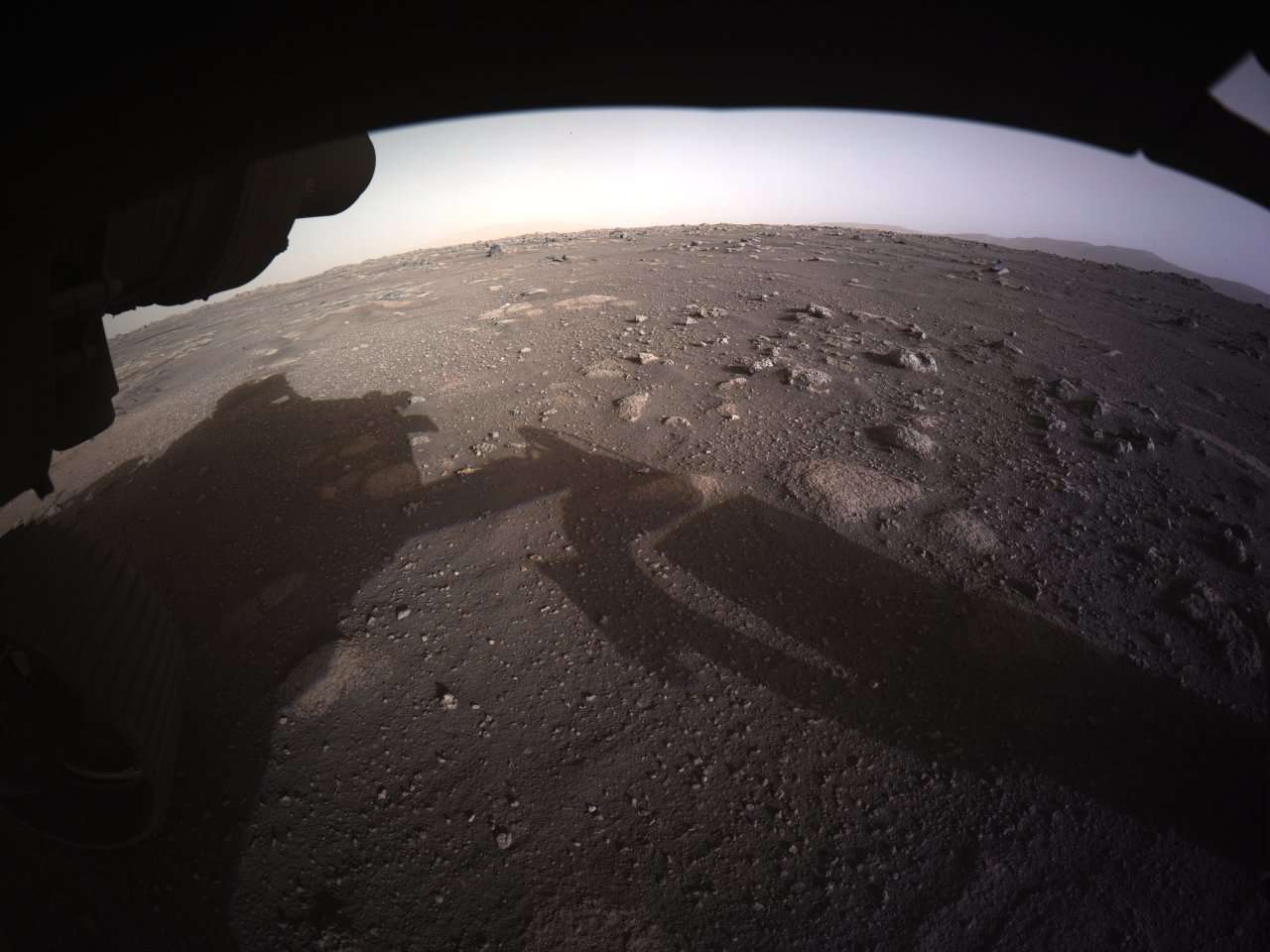 This shot from Persevarance’s hazard camera is the first color image taken by the rover, after the dust cover (that protected the camera from debris during landing) was removed. Credit: NASA/JPL-Caltech