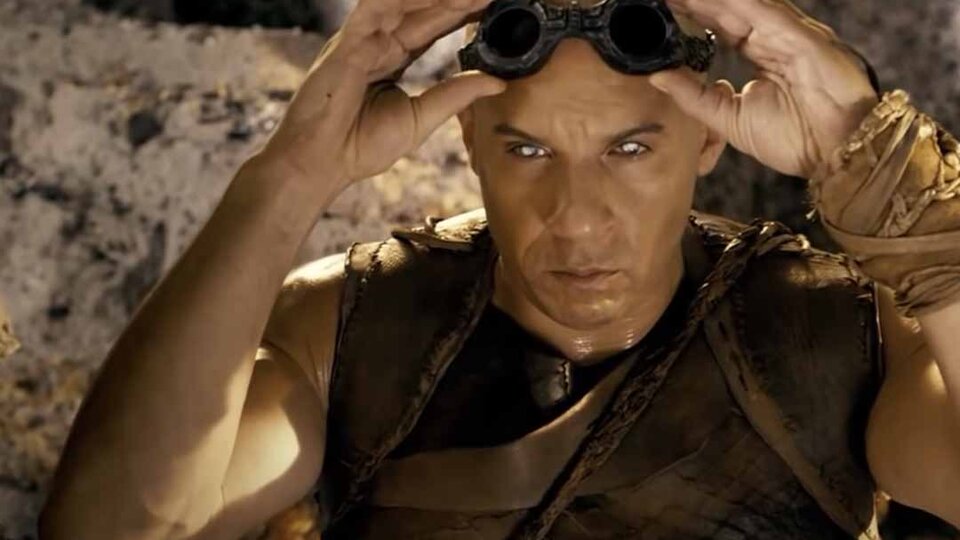 Riddick (Vin Diesel) adjust goggles on his forehead as his eyes glow white in Riddick (2013).
