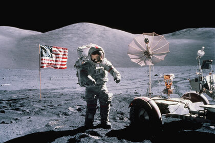 An astronaut with American flag on the surface of the moon