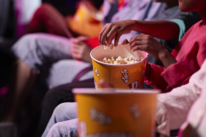 Friends sharing popcorn while sitting in theater
