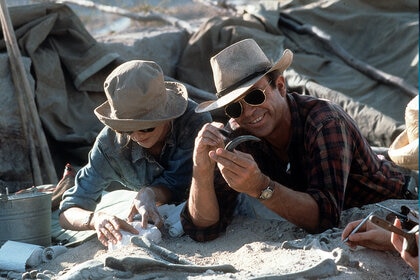Laura Dern and Sam Neill dig for fossils in a scene from the film Jurassic Park (1993)