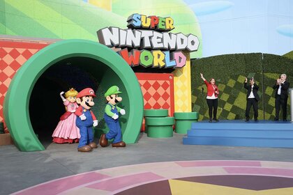 Princess Peach, Mario, and Luigi characters walk out of a green tunnel at Super Nintendo World Hollywood.