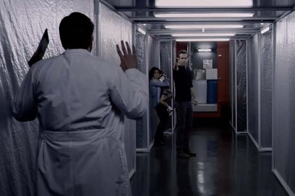 Ryan Reynolds pointing a gun at a man in a lab coat in Self/Less (2015)