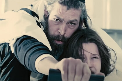 Tzadok (Matisyahu) shields Em (Natasha Calls) with his body in The Possession (2012)