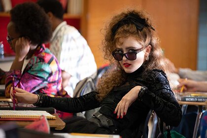Lisa Swallows (Kathryn Newton) wears all black and sits in a desk in Lisa Frankenstein (2023).