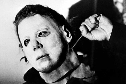 A masked Michael Myers (Nick Castle) holds a large nail to his neck in Halloween (1978)