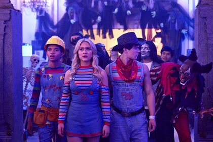 (l-r) Devon Evans (Bjorgvin Arnarson), Lexy Cross (Alyvia Alyn Lind), and Jake Wheeler (Zackary Arthur), all dressed as Chucky, walk past a man in a clown costume at a party in Chucky 304.
