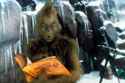 The Grinch (Jim Carrey) looks through a phone book on his icy mountain in How the Grinch Stole Christmas (2000).