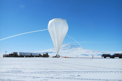 A large white balloon prepares to float over a snowy plane.